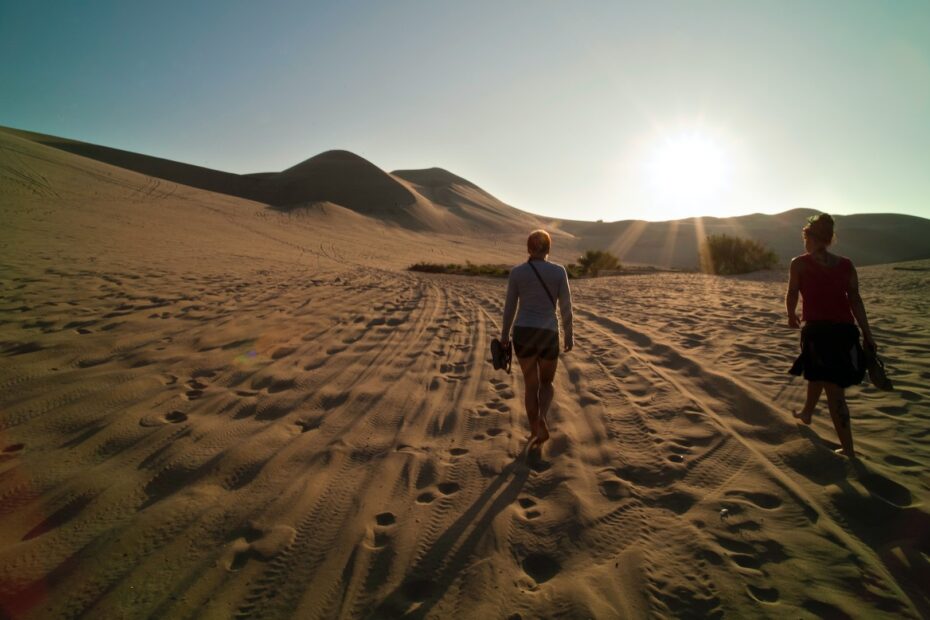 sunny and sandy scene with two women walking several feet apart